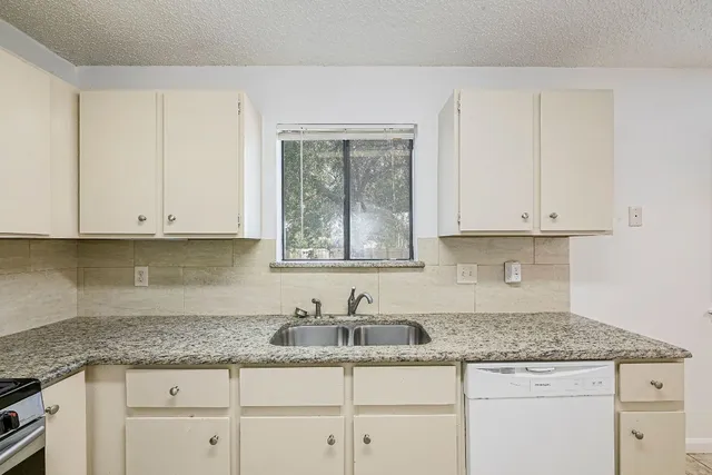 a kitchen with granite countertop white cabinets and a sink