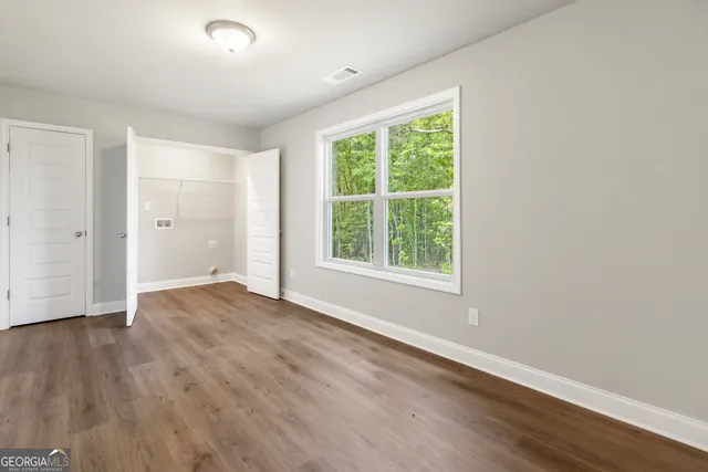 an empty room with wooden floor and windows