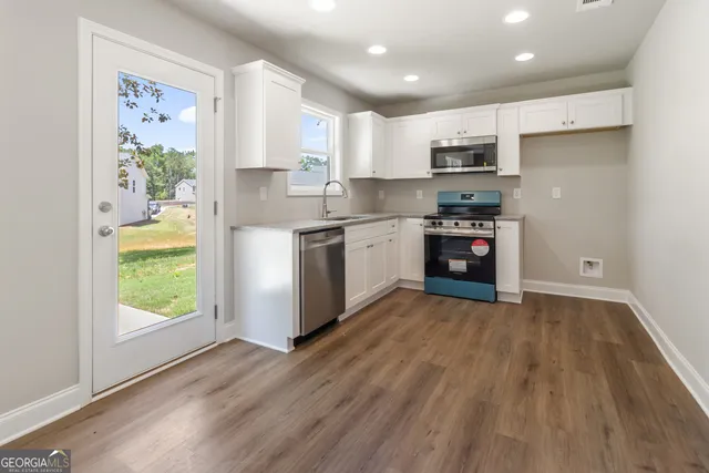 a kitchen with stainless steel appliances granite countertop a refrigerator a stove top oven a sink and dishwasher with wooden floor