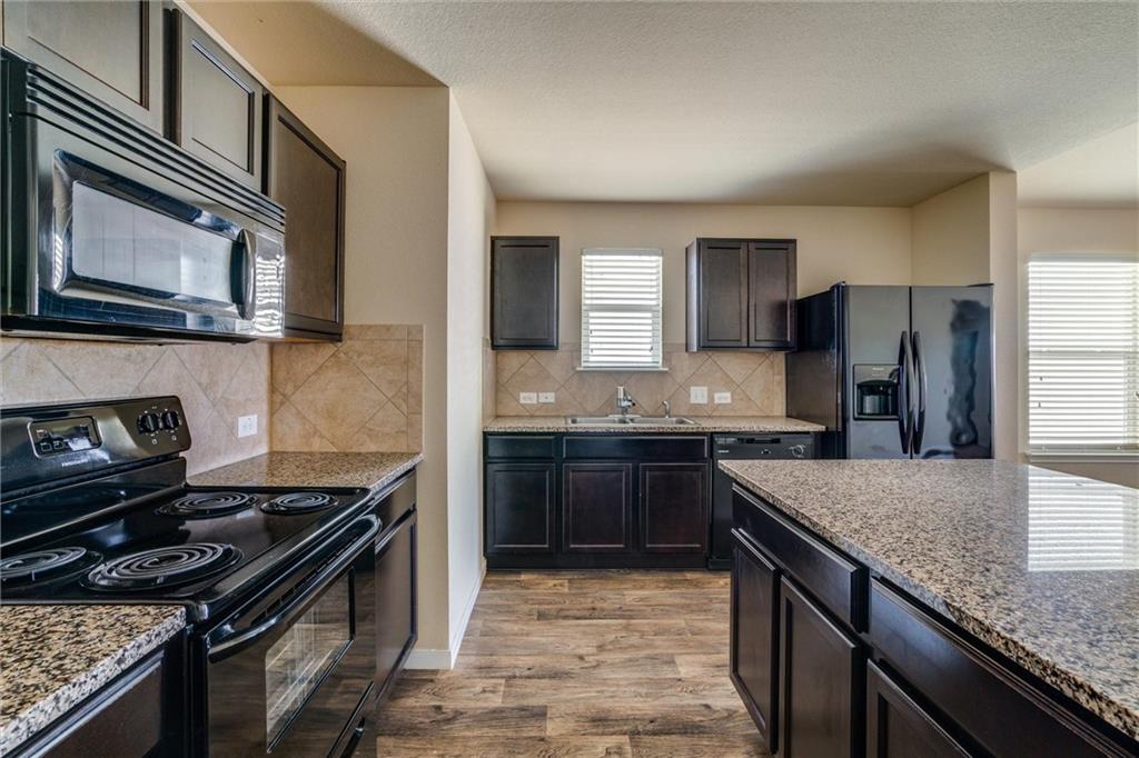 11704 Andesite Road Manor, TX 78653 - Photo 13 of 30 a kitchen with a stove and a microwave