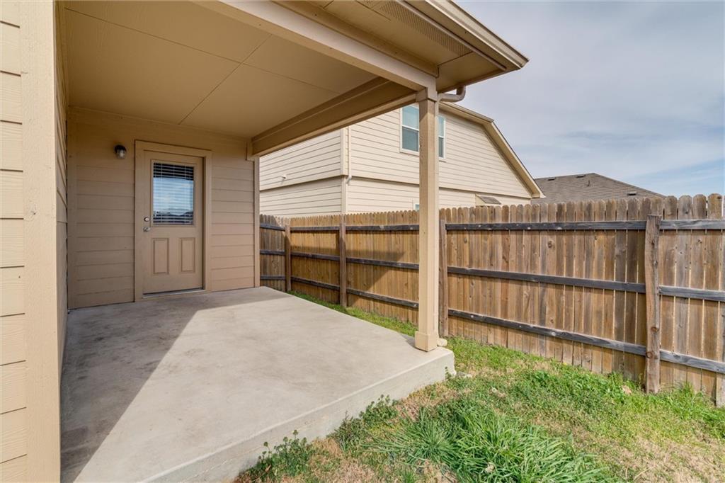 11704 Andesite Road Manor, TX 78653 - Photo 26 of 30 a view of backyard with small cabin and wooden fencing