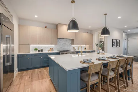 a kitchen with stainless steel appliances granite countertop a sink a stove a refrigerator a dining table and chairs with wooden floor
