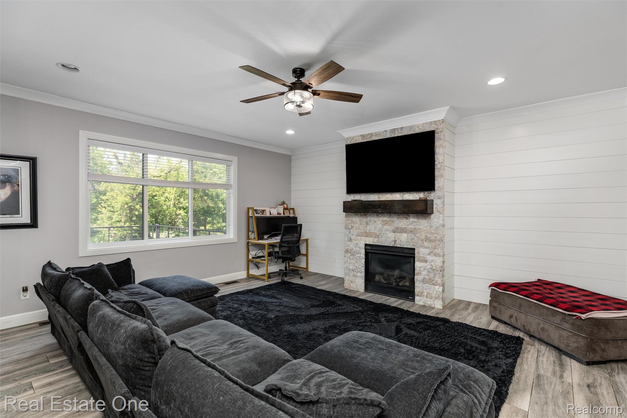 2983 28 Mile Road Washington, MI 48094 - Photo 16 of 54 Living area featuring an accent wall with shiplap paneling and a stacked stone fireplace with a wood-finish mantel