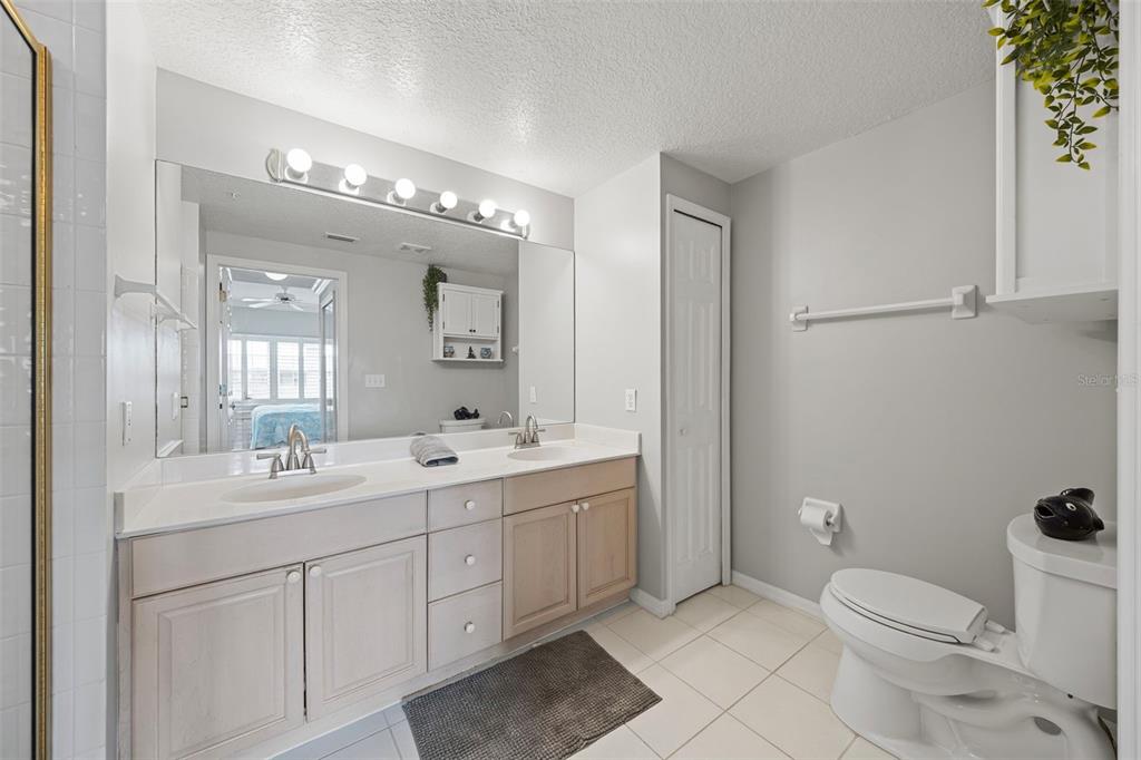 399 150th Avenue, Unit 309 Madeira Beach, FL 33708 - Photo 14 of 43 a bathroom with a toilet a sink a mirror and a shower