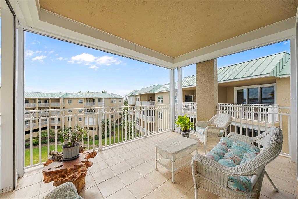 399 150th Avenue, Unit 309 Madeira Beach, FL 33708 - Photo 25 of 43 a view of a patio with couches chairs and wooden floor