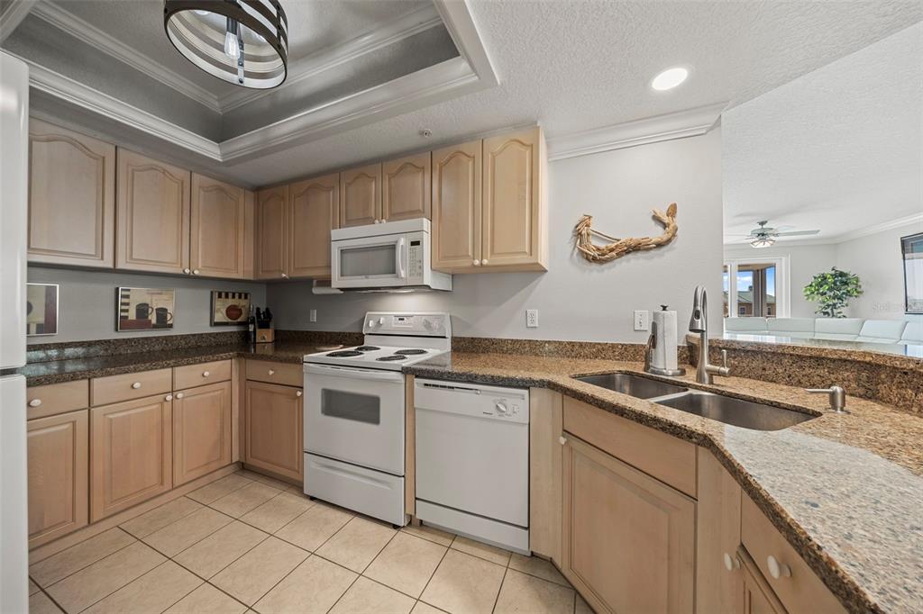 399 150th Avenue, Unit 309 Madeira Beach, FL 33708 - Photo 9 of 43 a kitchen with stainless steel appliances granite countertop a sink a stove and cabinets