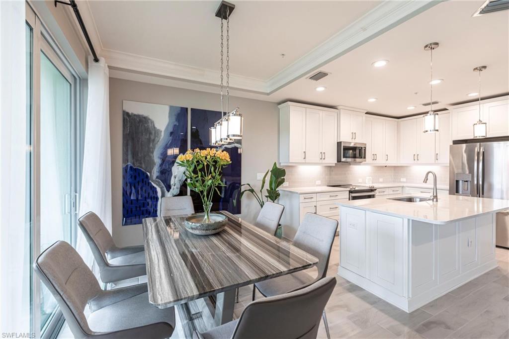 2319 Sawyers Hill Road, Unit 703 Naples, FL 34120 - Photo 12 of 35 a kitchen with stainless steel appliances kitchen island granite countertop a dining table chairs and white cabinets