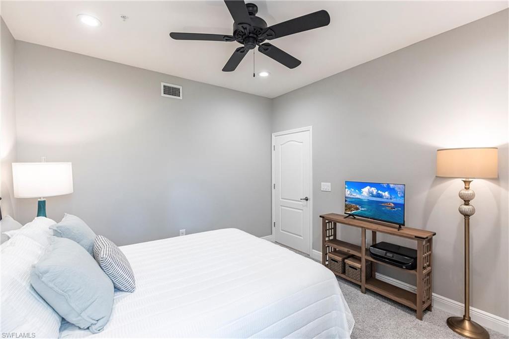 2319 Sawyers Hill Road, Unit 703 Naples, FL 34120 - Photo 24 of 35 a bedroom with a bed and a chandelier