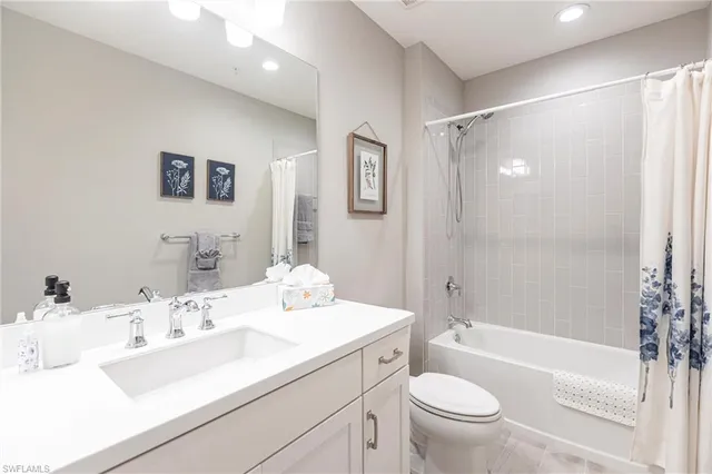 a bathroom with a bathtub shower sink vanity mirror and toilet