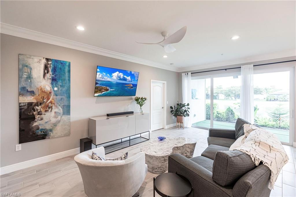 2319 Sawyers Hill Road, Unit 703 Naples, FL 34120 - Photo 3 of 35 a living room with furniture a large window and a flat screen tv