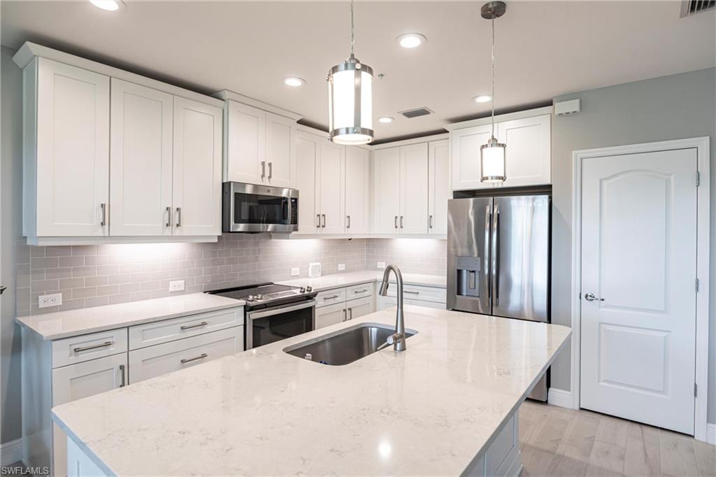 2319 Sawyers Hill Road, Unit 703 Naples, FL 34120 - Photo 6 of 35 a kitchen with stainless steel appliances kitchen island granite countertop a refrigerator oven a sink dishwasher and white cabinets with wooden floor