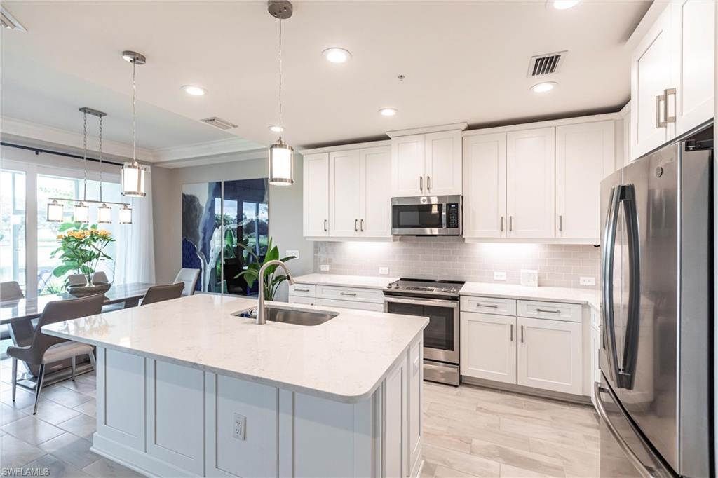 2319 Sawyers Hill Road, Unit 703 Naples, FL 34120 - Photo 7 of 35 a kitchen with stainless steel appliances kitchen island granite countertop a sink a stove a refrigerator and cabinets
