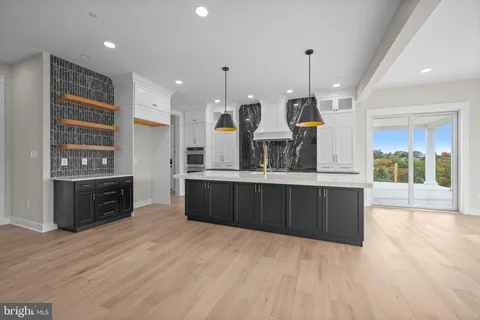a kitchen with stainless steel appliances kitchen island granite countertop a refrigerator a stove top oven and a wooden floors