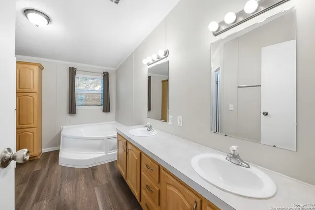 a bathroom with a double vanity sink a mirror and a bathtub