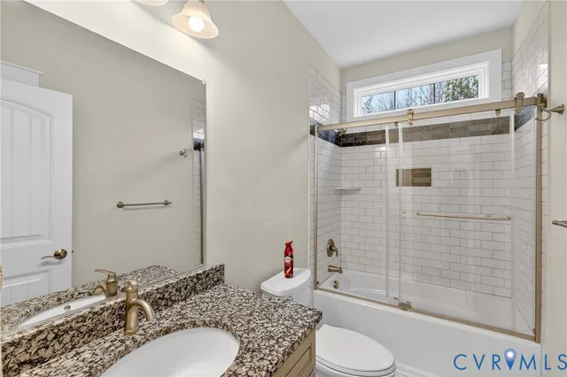 a bathroom with a granite countertop sink toilet a mirror and shower