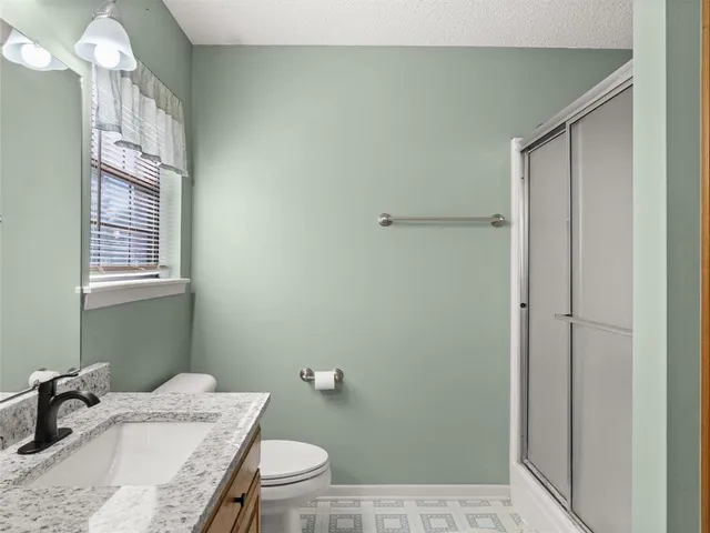 a bathroom with a granite countertop sink a toilet and shower
