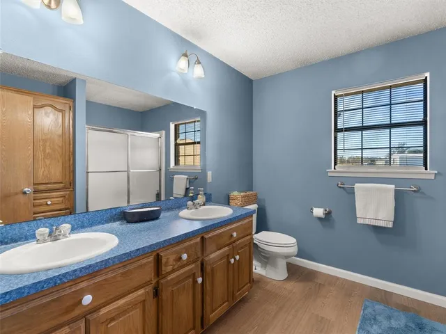 a bathroom with a granite countertop sink a large mirror a toilet and a window