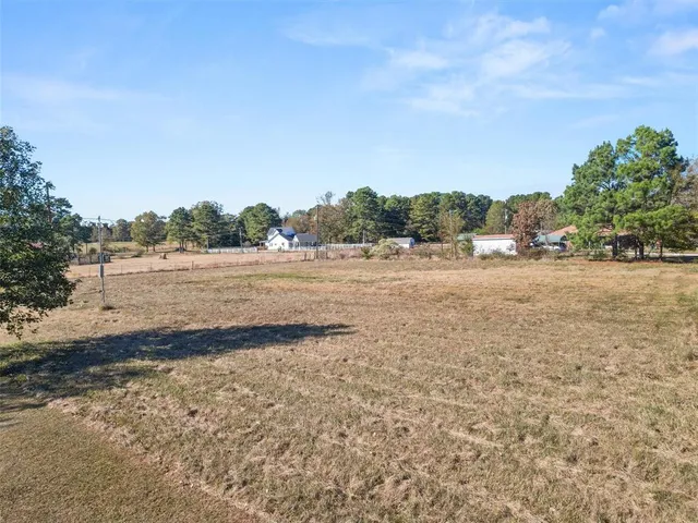 a view of dirt field with trees in background