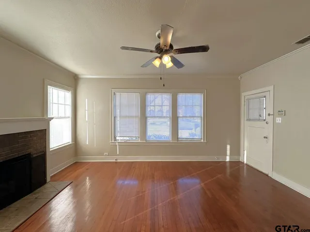 a view of an empty room with a window and wooden floor