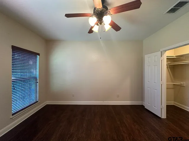 a view of an empty room with a window and wooden floor