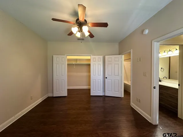 an empty room with wooden floor closet and windows