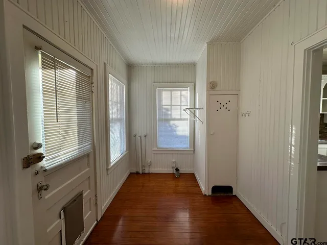 a view of a hallway with wooden floor and a bathroom