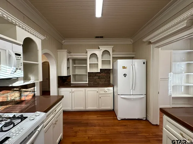 a kitchen with stainless steel appliances granite countertop a refrigerator a stove and a sink with wooden floor