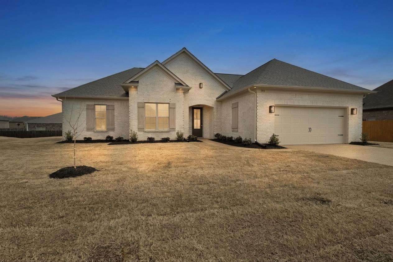 View of front of house with an attached garage, brick siding, concrete driveway, and roof with shingles
