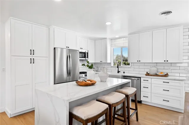 a kitchen with a refrigerator a stove a sink and white cabinets with wooden floor