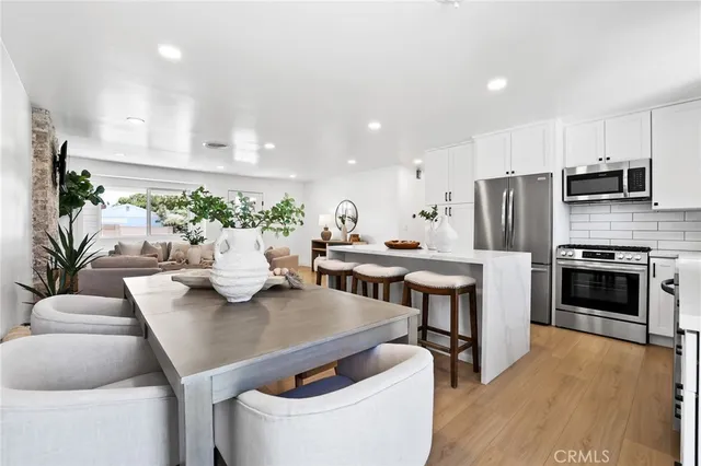 a kitchen with stainless steel appliances kitchen island granite countertop a table chairs stove and white cabinets