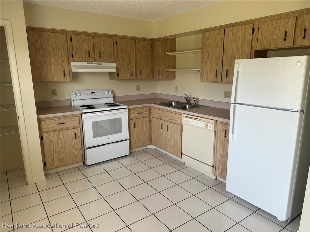 7422 Valencia Road Sebring, FL 33876 - Photo 6 of 15 a kitchen with white cabinets a sink and white appliances