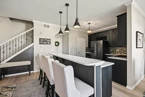 a kitchen with stainless steel appliances kitchen island a dining table chairs and white cabinets