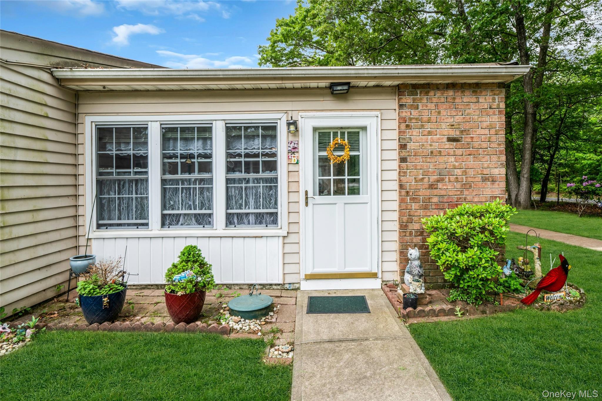 View of exterior entry with a lawn and brick siding