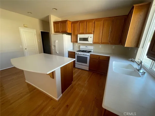 a kitchen with stainless steel appliances a refrigerator a sink a stove a microwave a counter space and wooden floor