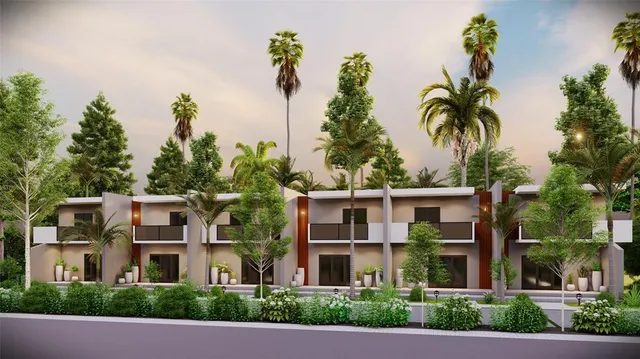 a front view of a residential apartment building with a yard and potted plants