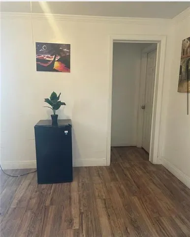 an empty room with wooden floor and hallway