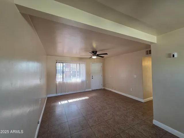 an empty room with windows and fan