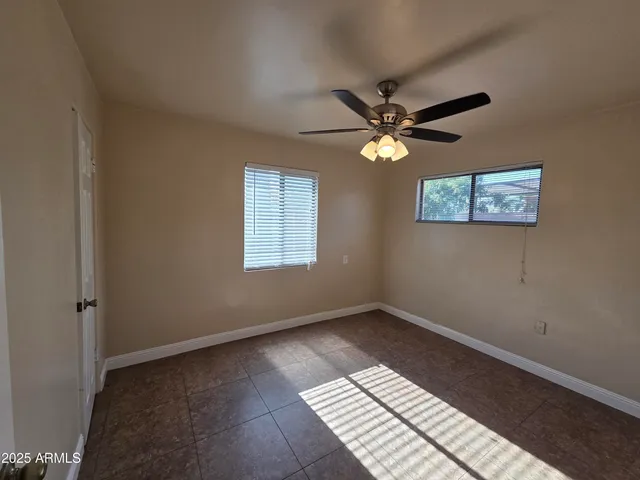 an empty room with windows and fan