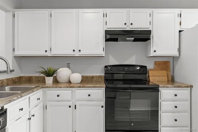a kitchen with granite countertop white cabinets and black appliances