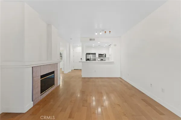 a view of a livingroom with wooden floor and a kitchen