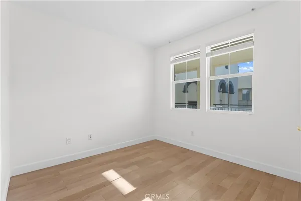 a view of an empty room with wooden floor and windows