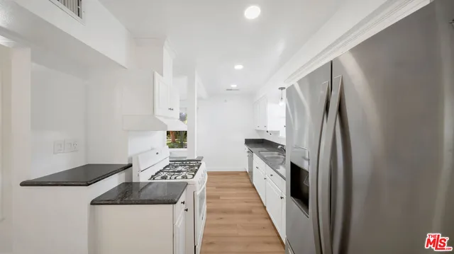 a kitchen with stainless steel appliances granite countertop a refrigerator and a stove
