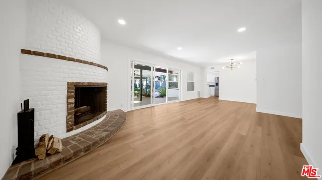 a view of empty room with wooden floor and fireplace