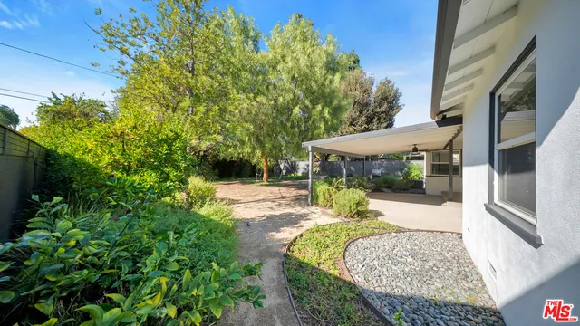 a patio with table and chairs and potted plants
