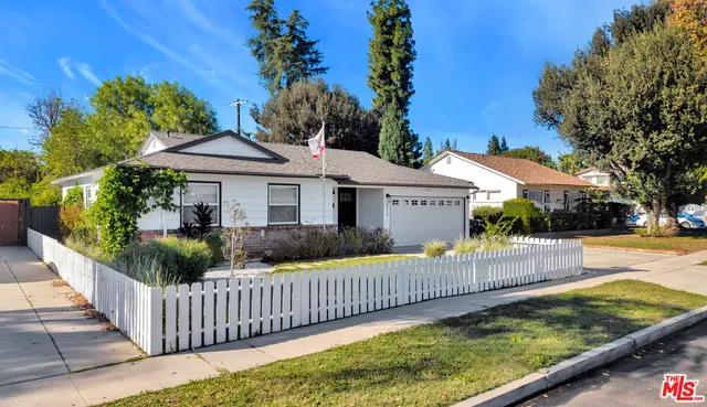 a view of a house with wooden fence next to a yard