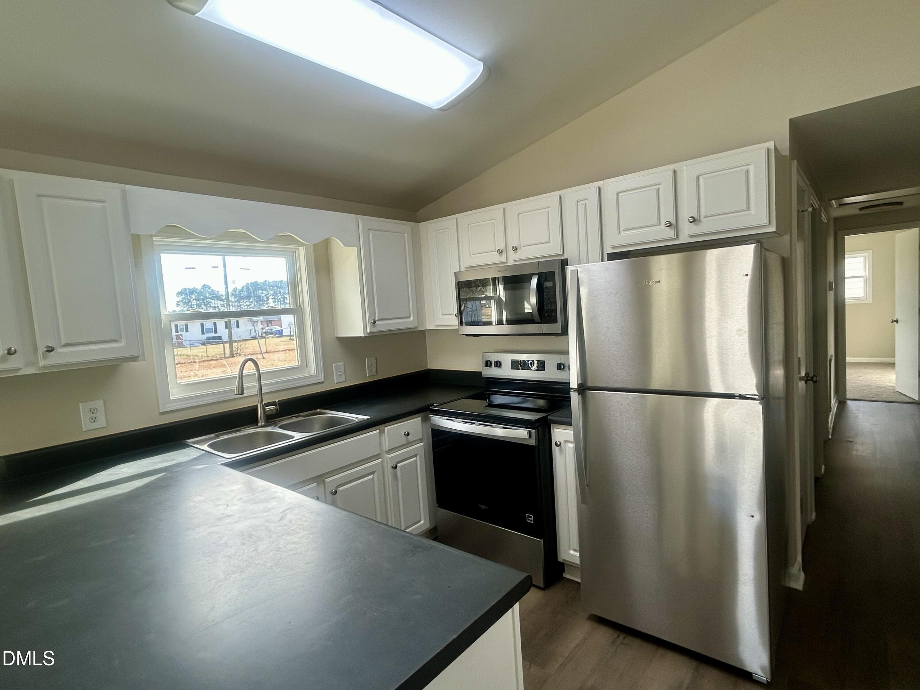 403 South Market Street Benson, NC 27504 - Photo 6 of 18 a kitchen with granite countertop a refrigerator a sink a stove and cabinets