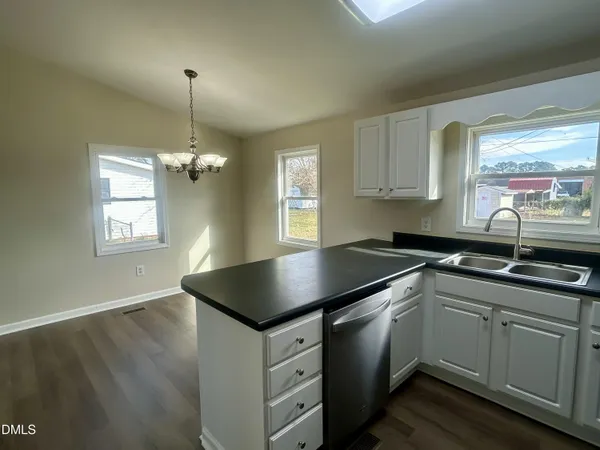 a kitchen with granite countertop white cabinets a sink dishwasher and a stove with wooden floor