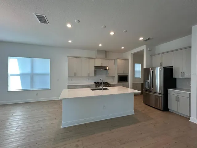 a large kitchen with stainless steel appliances a large counter top and a stove