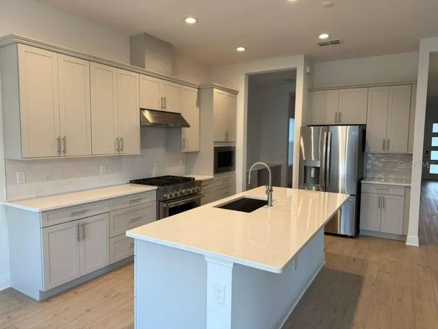 a kitchen with stainless steel appliances kitchen island a refrigerator sink and cabinets