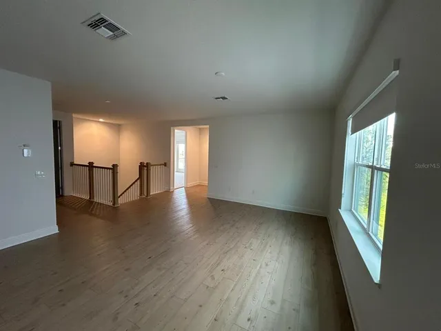 an empty room with wooden floor and windows